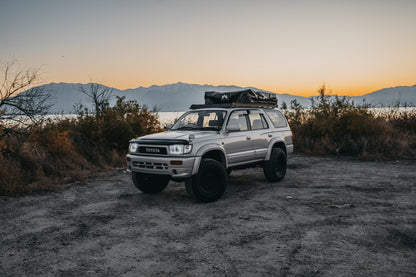 Closed Soft Shell rooftop tent on a Hilux Surf, parked at a lake with a sunrise